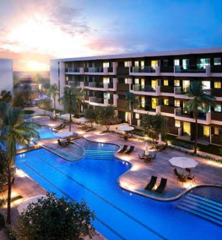 a hotel with a large swimming pool with palm trees at Loft Mana Experience INN in Ipojuca