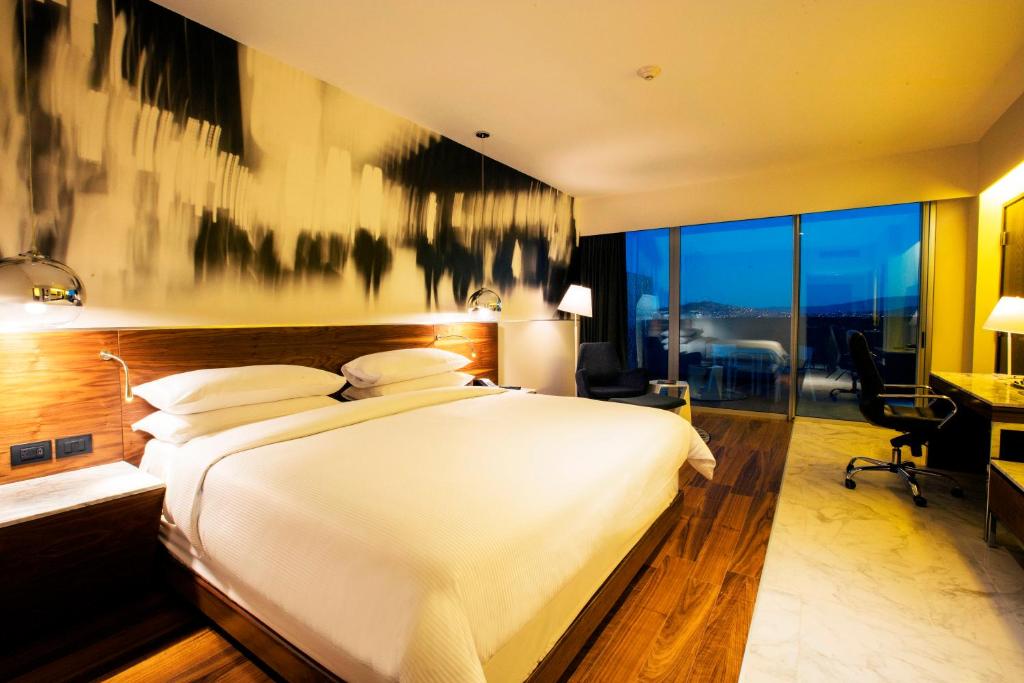 a bedroom with a large white bed and a desk at Krystal Urban Guadalajara in Guadalajara