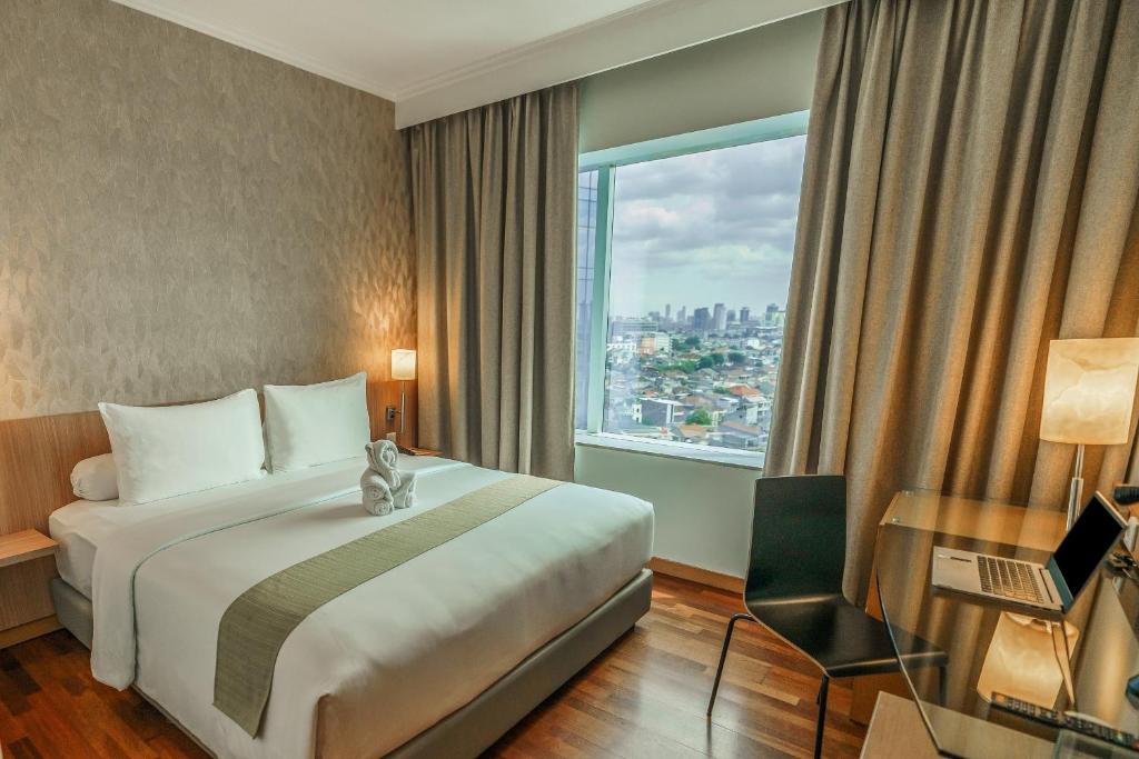 Rúm í herbergi á Hotel KIMAYA Slipi Jakarta By HARRIS