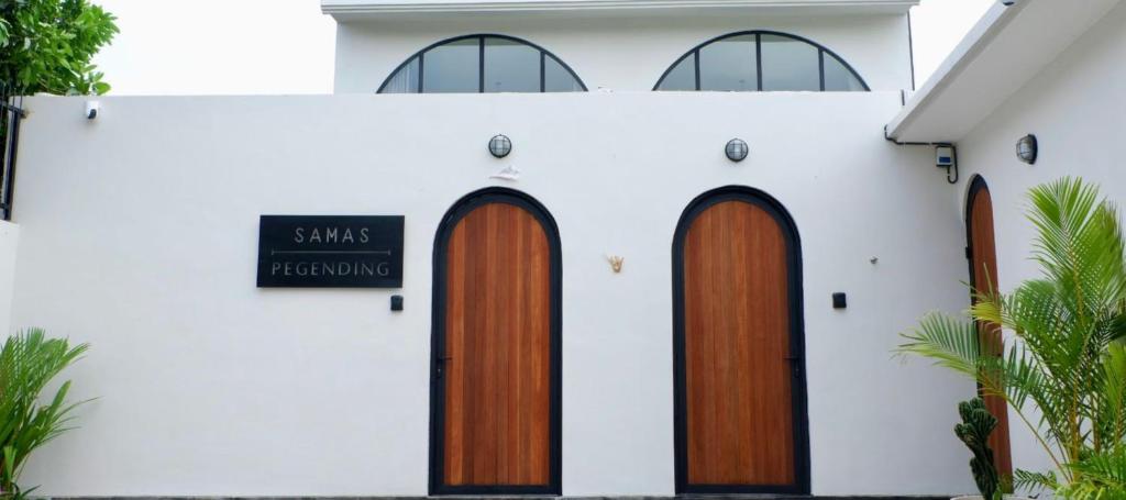 Un edificio blanco con puertas de madera y un cartel en él. en Modern loft by Samas Group, en Dalung