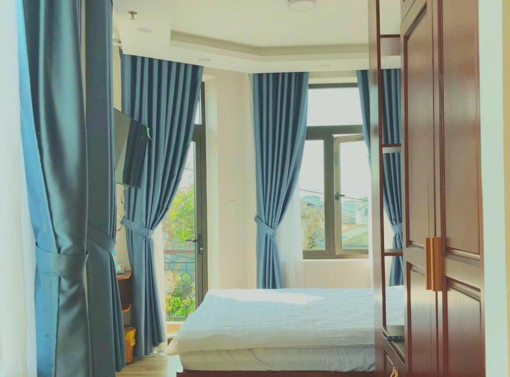 a bedroom with blue curtains and a bed and a window at Moonlight House in Da Thanh