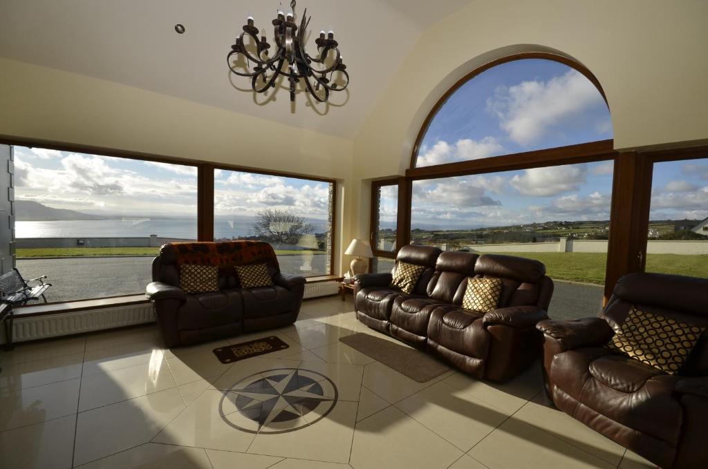 a living room with leather furniture and large windows at Templeview Lodge in Greencastle