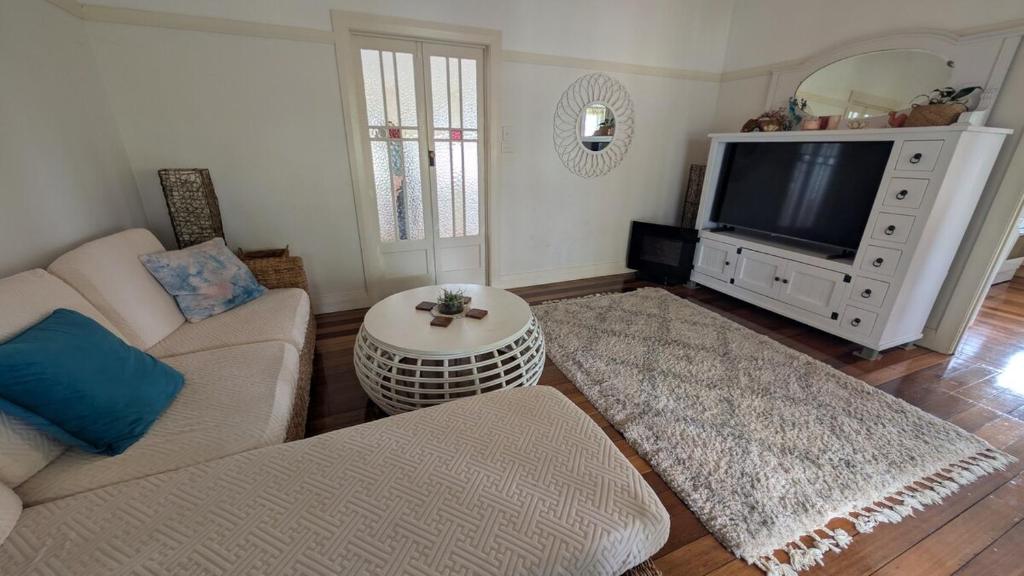 a living room with a couch and a tv at Yamba Somerset Cottage in Yamba