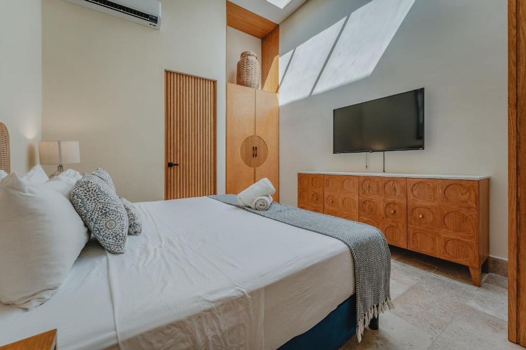 Un dormitorio con una cama con un televisor en la pared. en Casa Mara Reforma con alberca, en Mérida