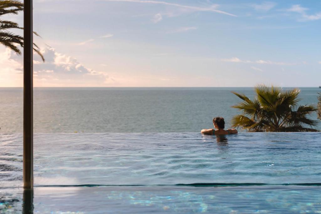 a man in a swimming pool overlooking the ocean at Hotel Continental in Santa Margherita Ligure