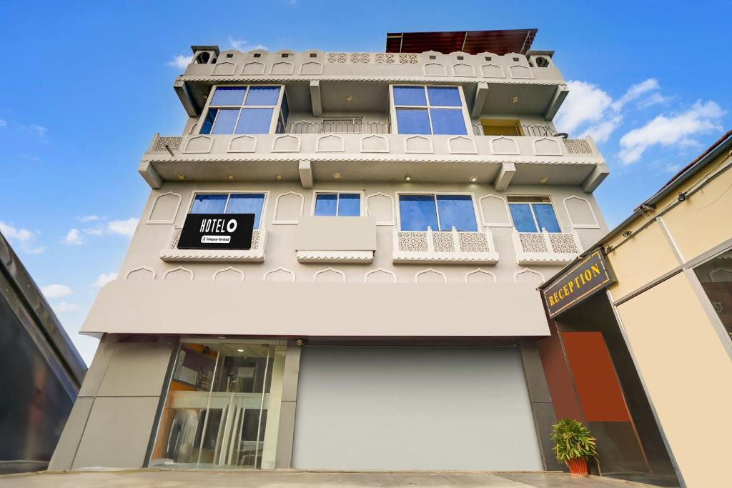 a tall white building with a sign on it at Super Hotel O JLN Marg Malviya Nagar Formerly Hotel Braj Haveli in Jaipur