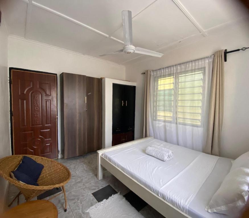 een slaapkamer met een bed, een stoel en een raam bij Serenity Eusy Diani in Ukunda