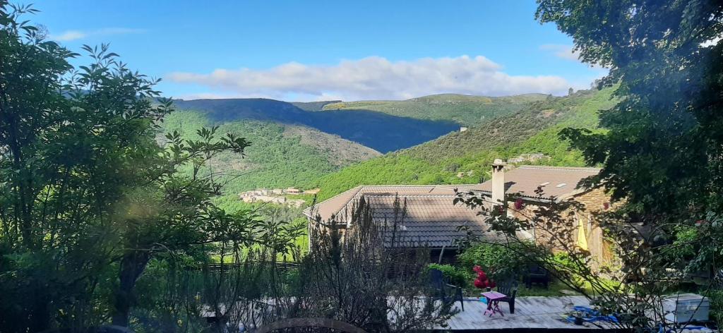 a house on a hill with mountains in the background at Le MàS du Plot in Sablières