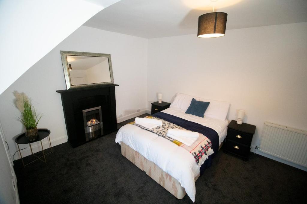 a bedroom with a bed with a fireplace and a mirror at Beautify Refurbished Large 3 Bed Terrace in Hawick