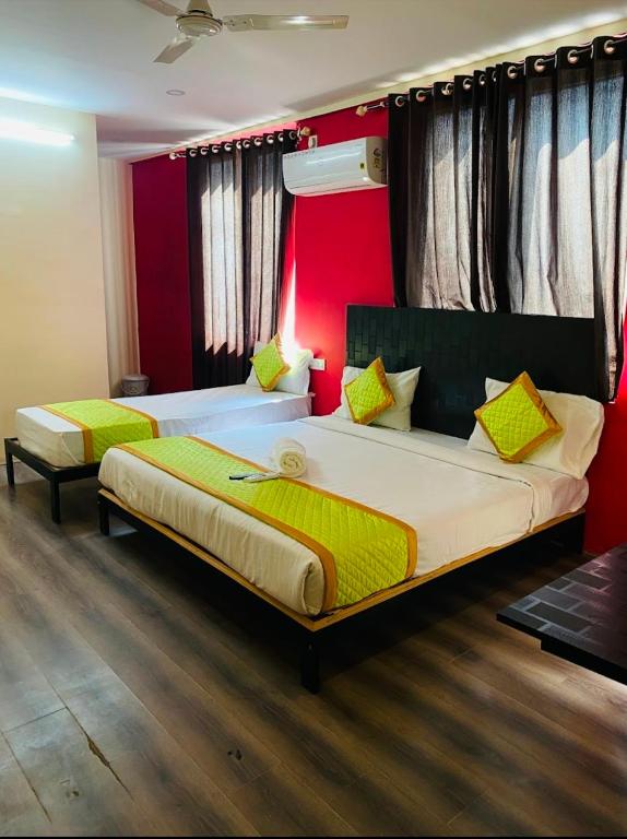 a bedroom with two beds and a red wall at Hotel Fusion Suites in Bangalore