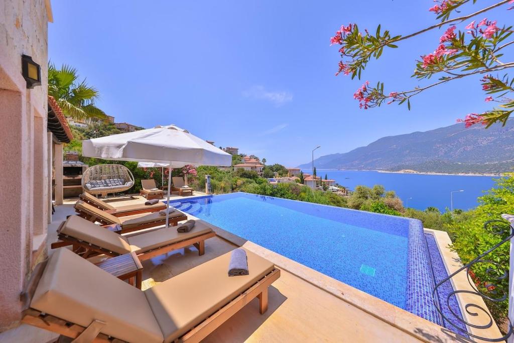 a swimming pool with chairs and an umbrella next to the water at Villa Nane in Kaş