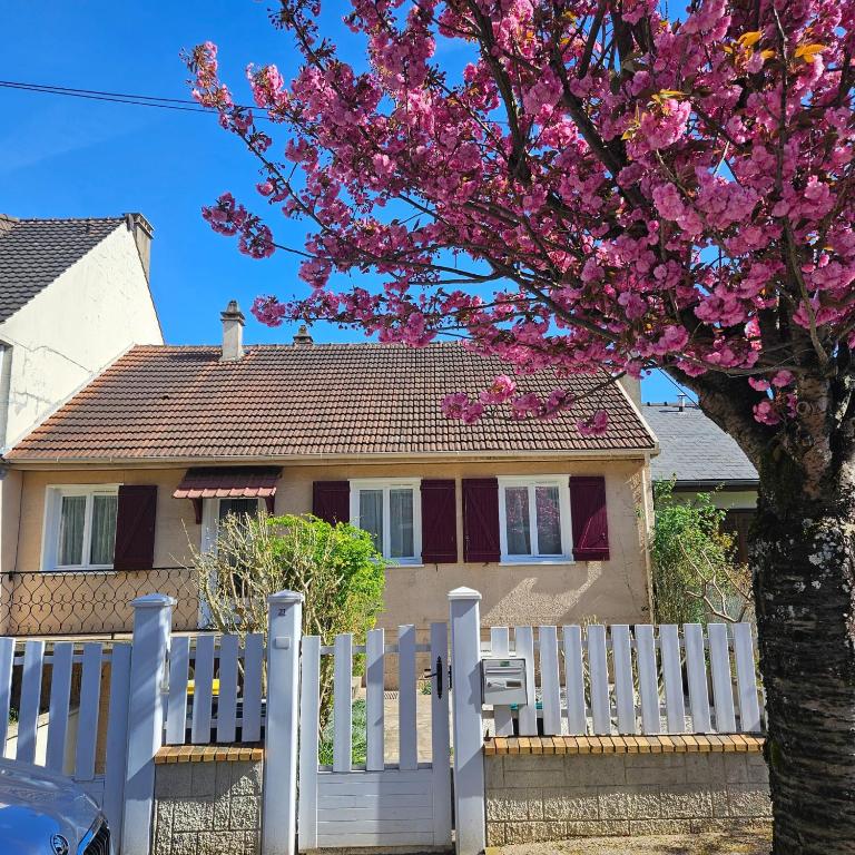 une clôture blanche devant une maison avec un arbre dans l'établissement Maison avec jardin proche Paris et Disney, à Pontault-Combault