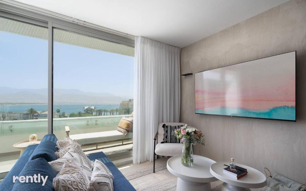 ein Wohnzimmer mit einer blauen Couch und einem großen Fenster in der Unterkunft Luxury Apartments And Studios At Sea Side By Rently in Eilat
