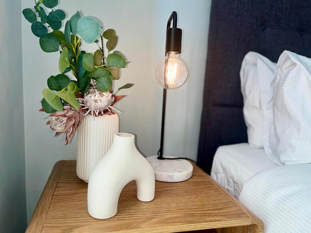 a table with a lamp and a vase on it at A city oasis - full apartment with balcony in Perth
