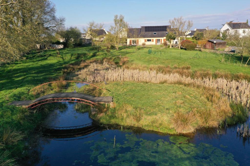 a bridge over a river with a field and houses at Maison très agréable in Pleyber-Christ
