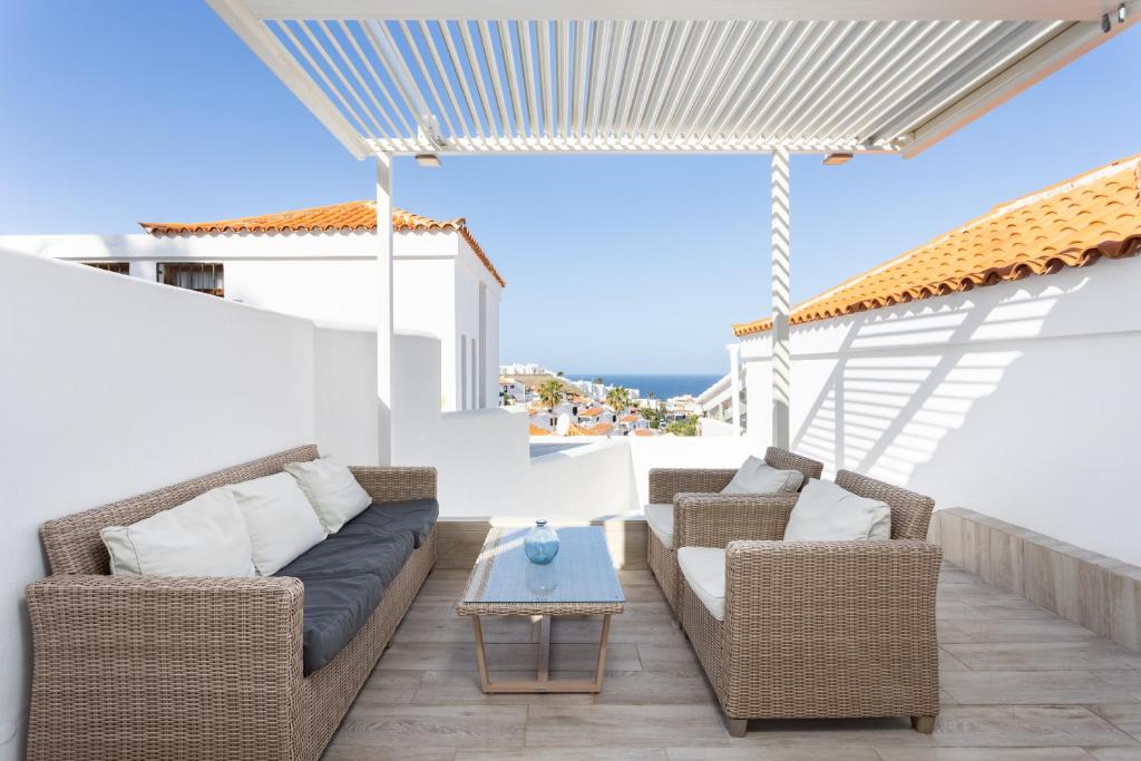 eine Terrasse mit zwei Korbstühlen und einem Tisch in der Unterkunft Home2Book Stunning Views Bungalow Costa Adeje in Adeje