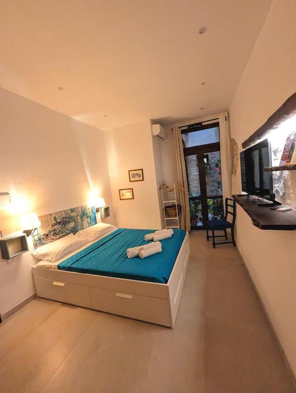 1 dormitorio con 1 cama con sábanas azules y TV en Casa di Leda 2, en Cagliari