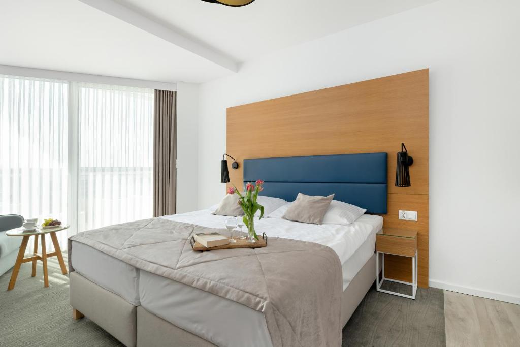 ein Schlafzimmer mit einem großen Bett mit blauem Kopfteil in der Unterkunft Seaside Park by Solarento in Kołobrzeg