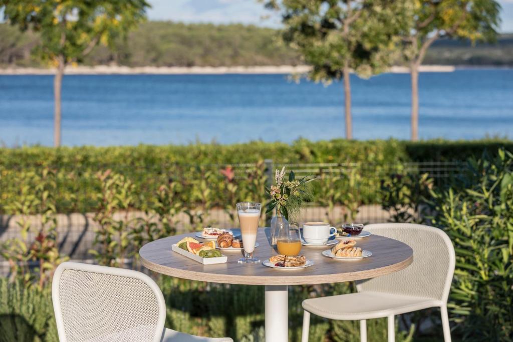 a table with food and drinks on it next to the water at Falkensteiner Hotel Park Punat in Punat