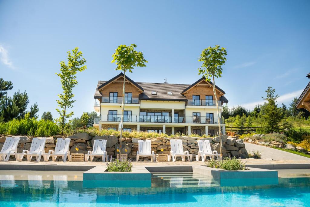a large house with chairs and a swimming pool at Skalnica - Apartamenty w Bieszczadach nad Soliną in Berezka