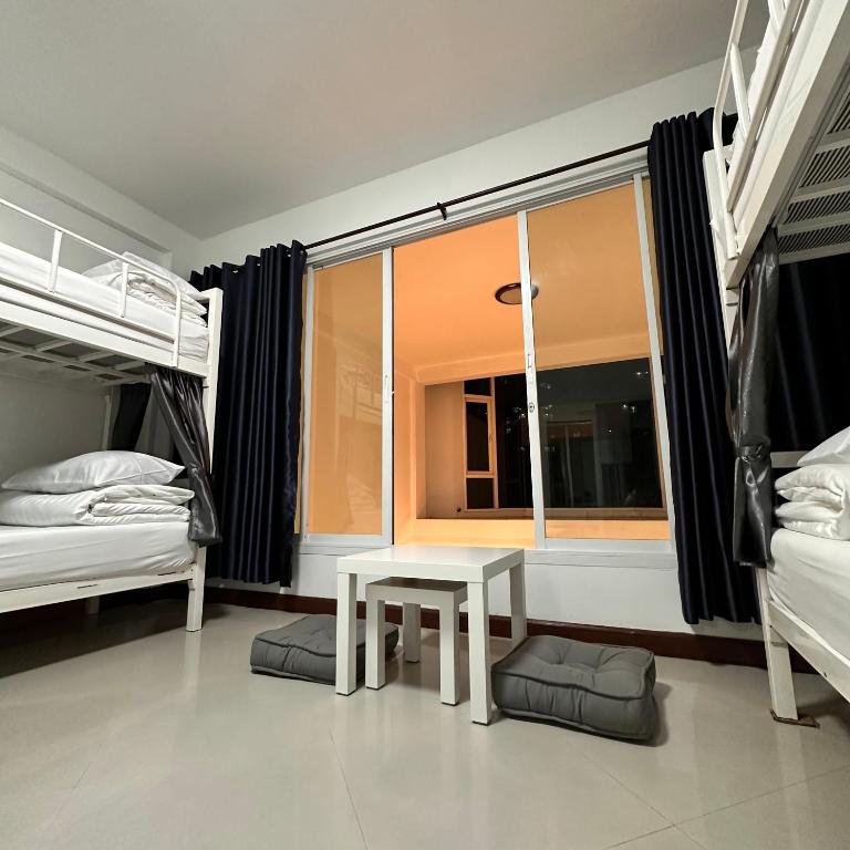 a bedroom with two bunk beds and a table in front of a window at 소다호스텔 Soda HosteL in Chiang Mai