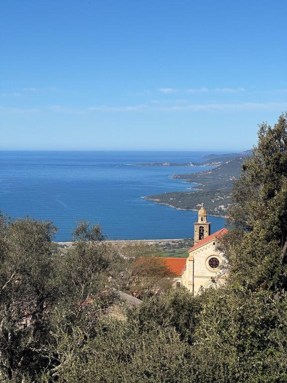 une église sur une colline à côté de l'océan dans l'établissement Tout confort à Viggianello, à Viggianello