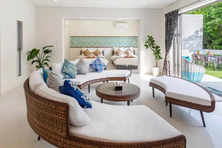 a living room with couches and tables and a couch at Carmus-チャームーズ- in Nakijin