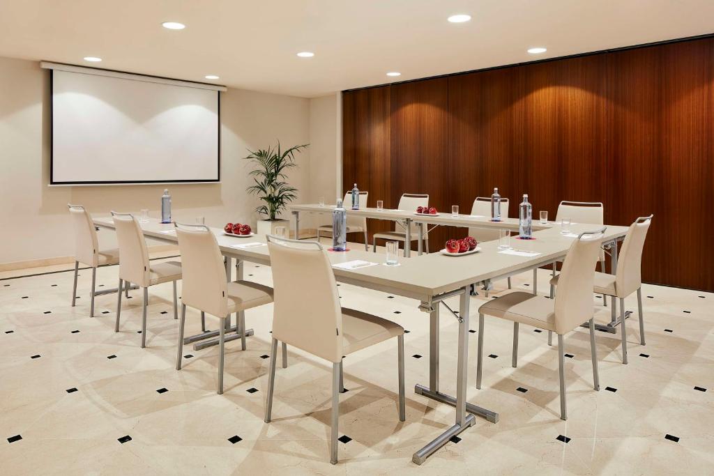 a conference room with a table and chairs and a screen at NH Collection Marbella in Marbella