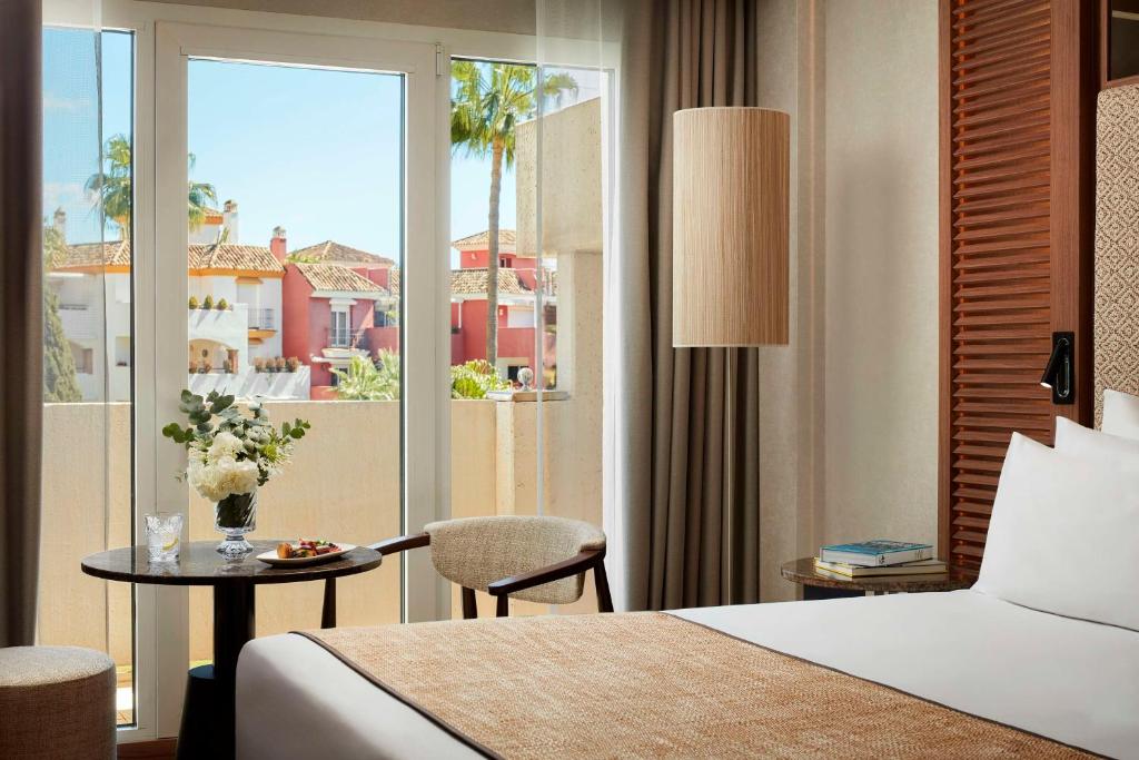 a hotel room with a bed and a table and a window at NH Collection Marbella in Marbella