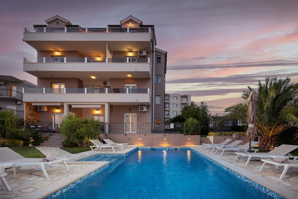 a villa with a swimming pool in front of a building at Sunny Garden Lux in Split