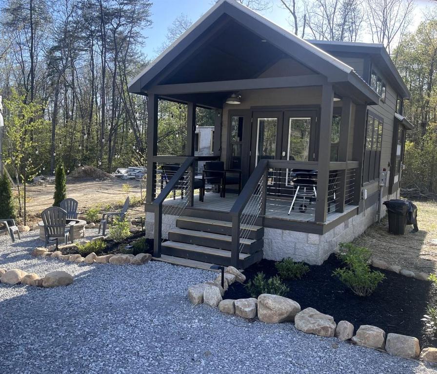 a small cabin with a porch and a table and chairs at Breathtaking Tiny House Settled Between Trees in Tracy City, Tennessee in Tracy City