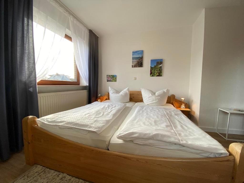 a large bed in a bedroom with a window at Stockrosenhuus in Westerland