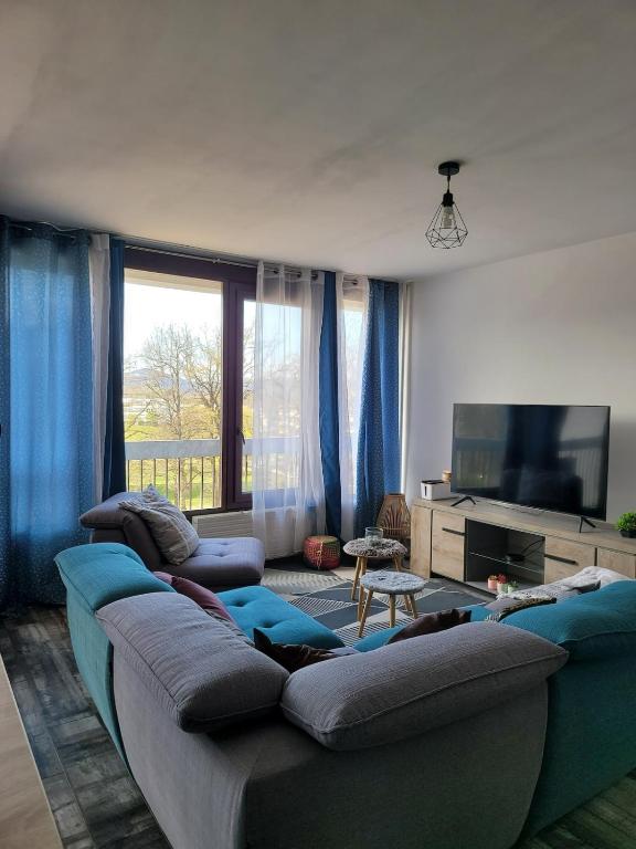 un salon avec un canapé bleu et une télévision dans l'établissement Appartement lumineux T2 près d'Annecy, à Annecy