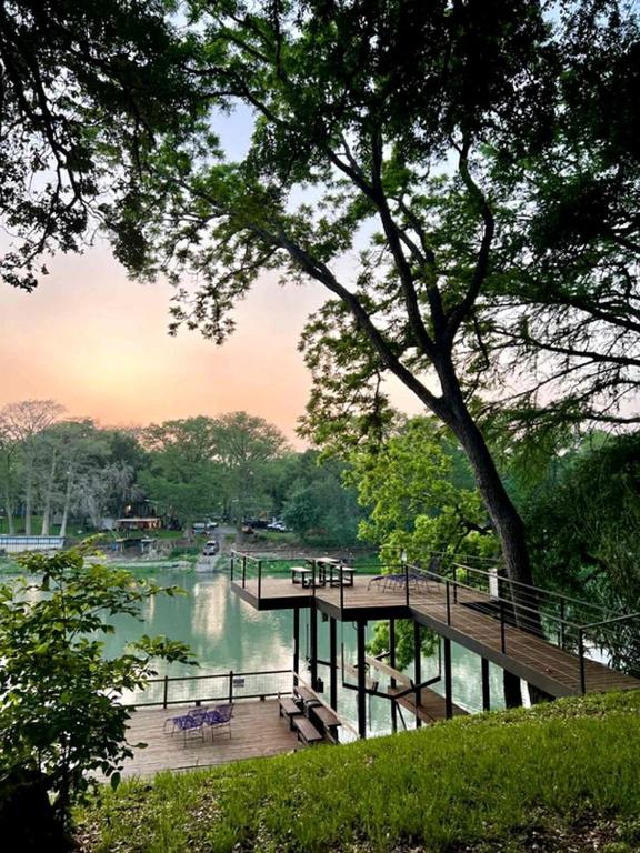 a wooden bridge over a river with benches on it at Riverfront Tiny House with Fire Pit in Seguin, Texas in Seguin