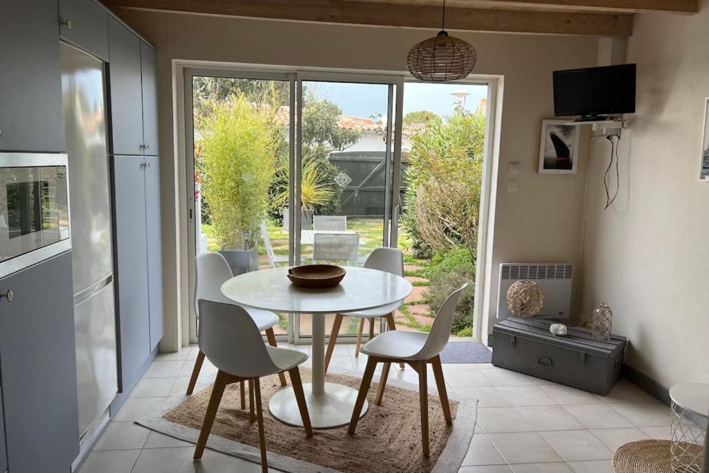 une cuisine avec une table et des chaises blanches ainsi qu'une fenêtre dans l'établissement Cozy retreat near the beach terraces and parking, à La Flotte