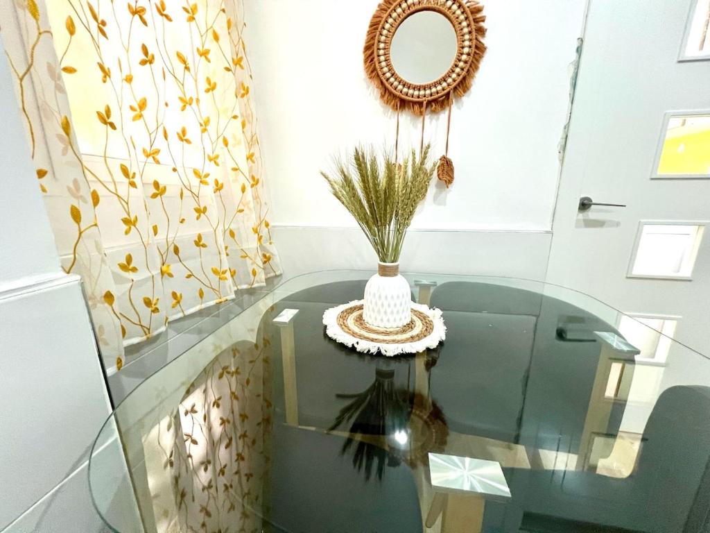 a glass table with a vase on top of it at Rosaleda Centro Apartamento in Málaga
