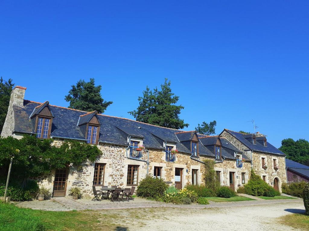 un grand bâtiment en pierre avec de nombreuses fenêtres dans l'établissement La Julerie, 4 Gîtes en Campagne avec Piscine, à Corseul