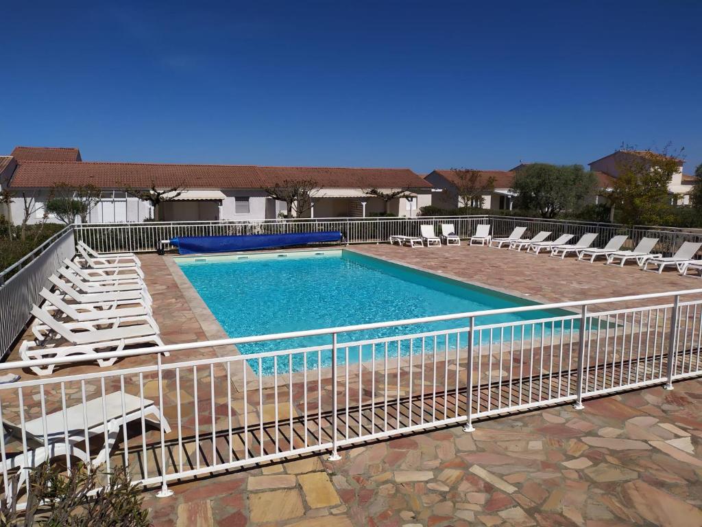 une piscine avec des chaises et une clôture dans l'établissement Mini villa T2, 200 m de la plage, piscine chauffée, jardin, à Prunete
