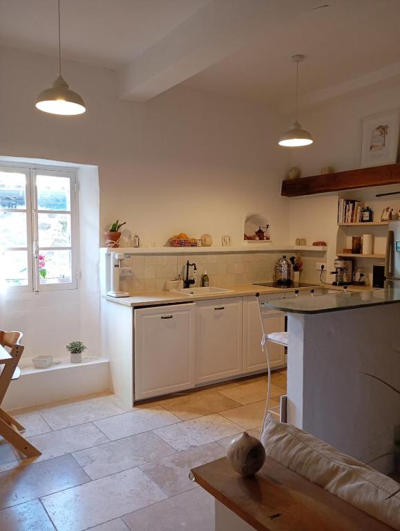 une grande cuisine avec des armoires blanches et une fenêtre dans l'établissement Maison climatisée au coeur du village, à Cagnes-sur-Mer