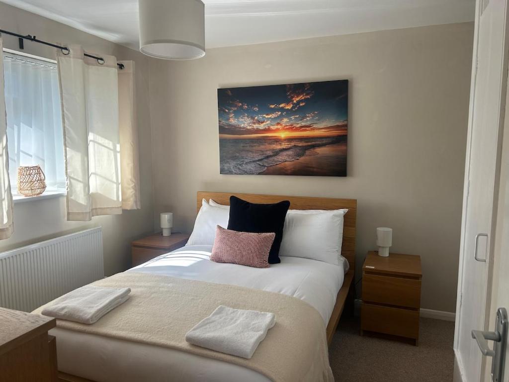 une chambre avec un lit et un tableau au mur dans l'établissement 2 Bedroom Townhouse near Cardiff Bay and City Centre with Garden and Parking, à Cardiff