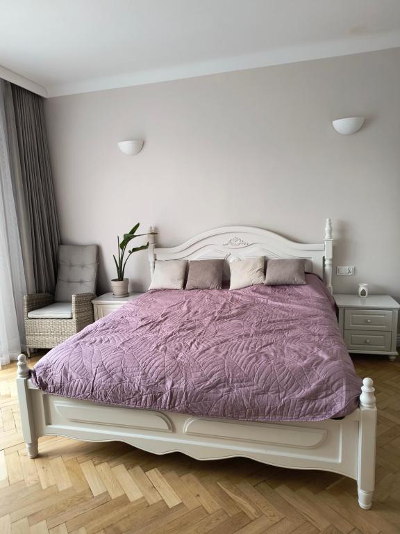 1 dormitorio con cama blanca y edredón morado en Apartament Mickiewicza, en Olsztyn