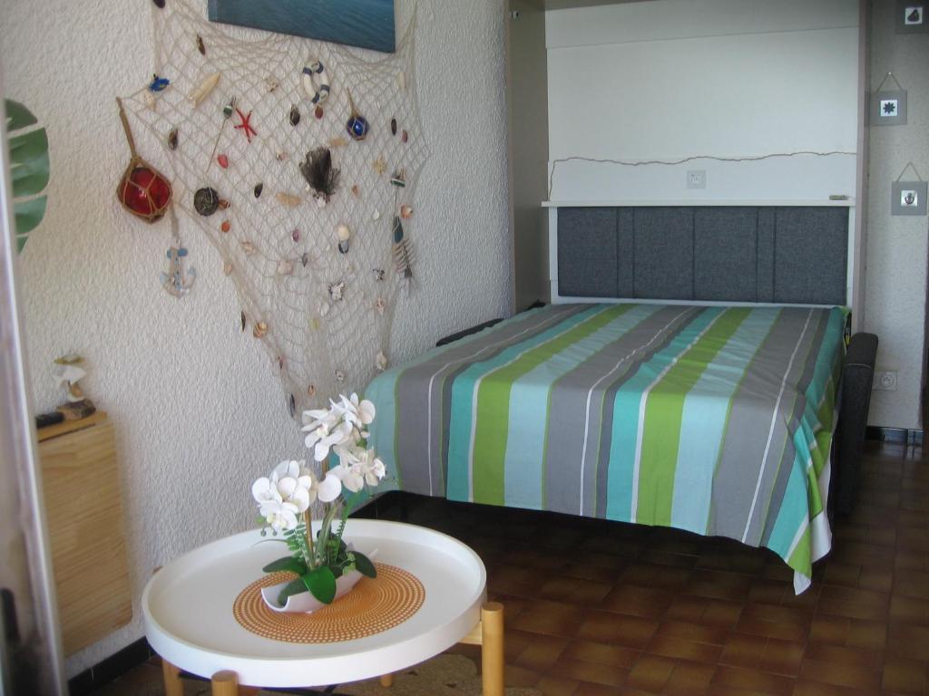 a bedroom with a bed and a table with flowers on it at Studio vue sur la mer au 6ème et dernier étage in Canet-en-Roussillon