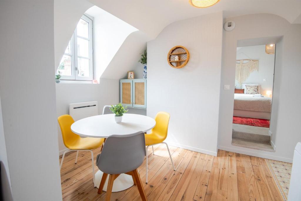une salle à manger avec une table blanche et des chaises jaunes dans l'établissement AU VINCI Appartement 4 personnes, à Amboise