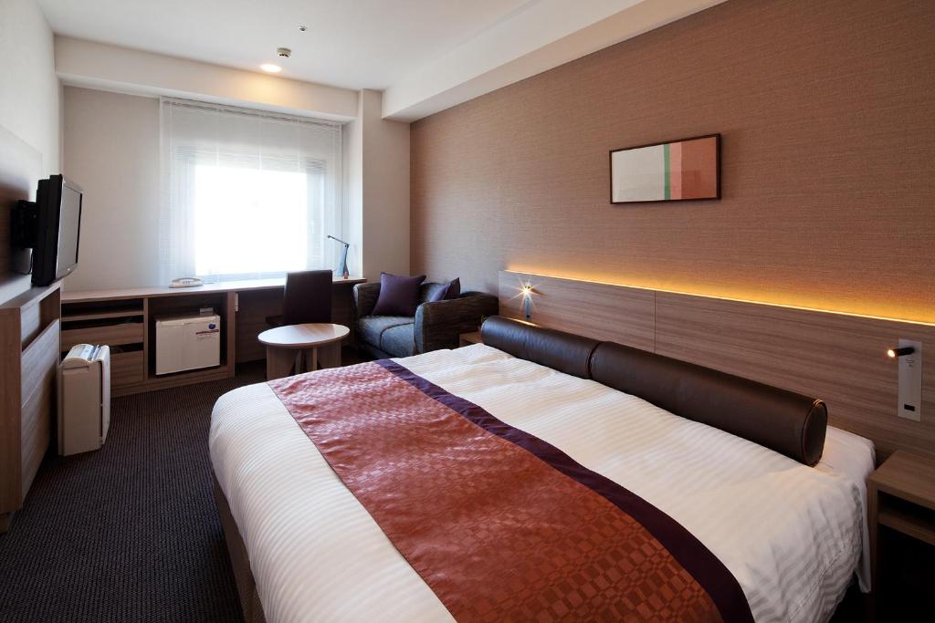 a hotel room with a large bed and a chair at Ueda Tokyu REI Hotel in Ueda