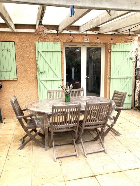 une table en bois avec des chaises et un vase de fleurs dans l'établissement Beach house - 6 people - parking, à Frontignan
