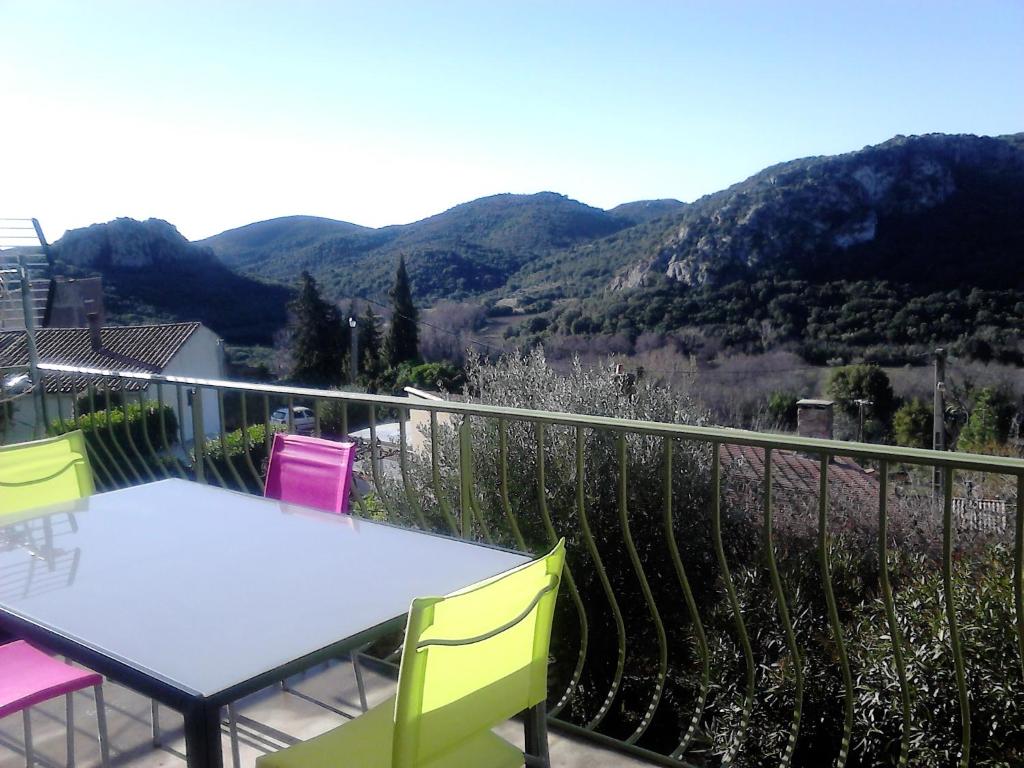 a table and chairs on a balcony with mountains at Maison vue Panoramique in Vailhan