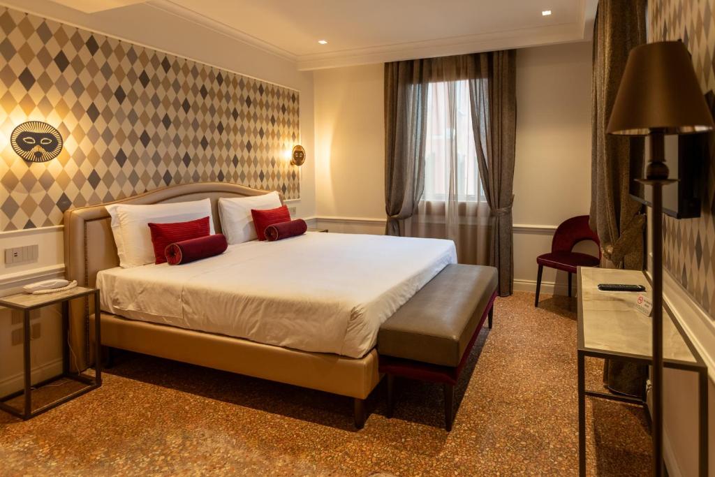 a hotel room with a bed with red pillows at Hotel Arlecchino in Venice