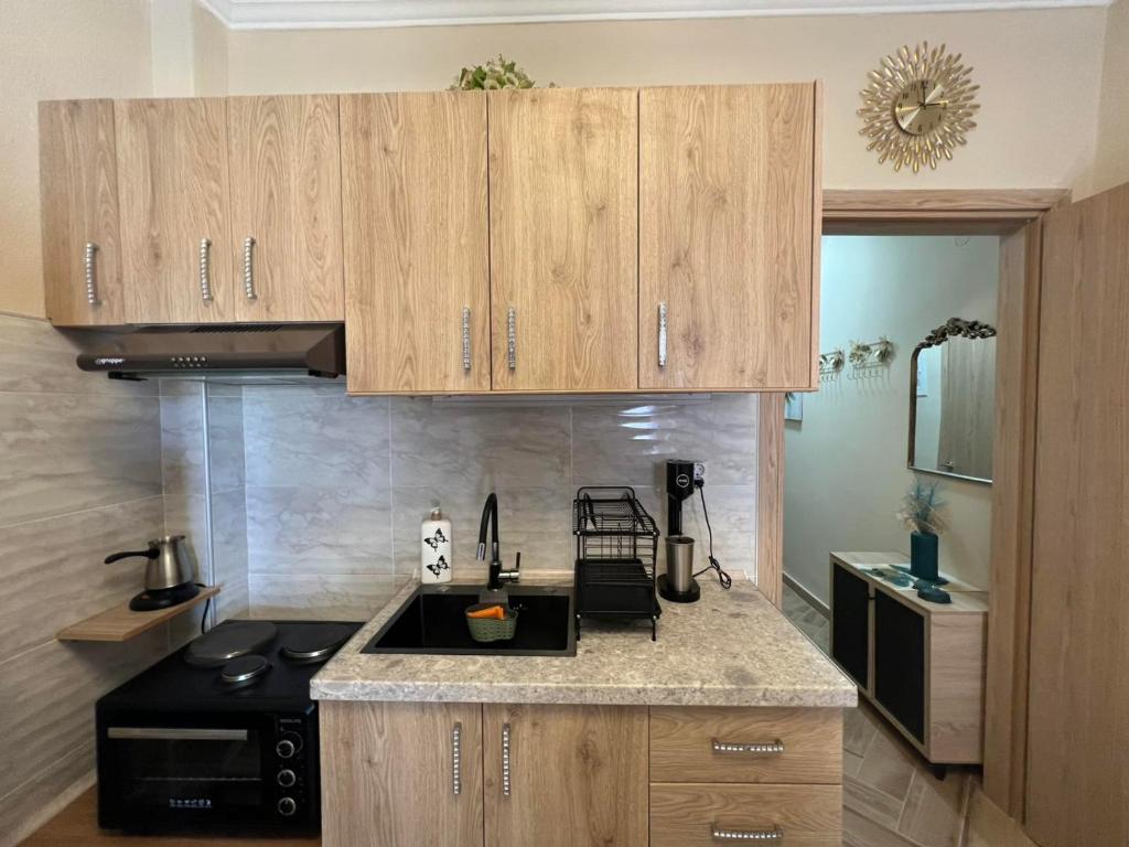 a kitchen with wooden cabinets and a black stove at Blue Horizon Seaside Studio in Nea Kalikratia