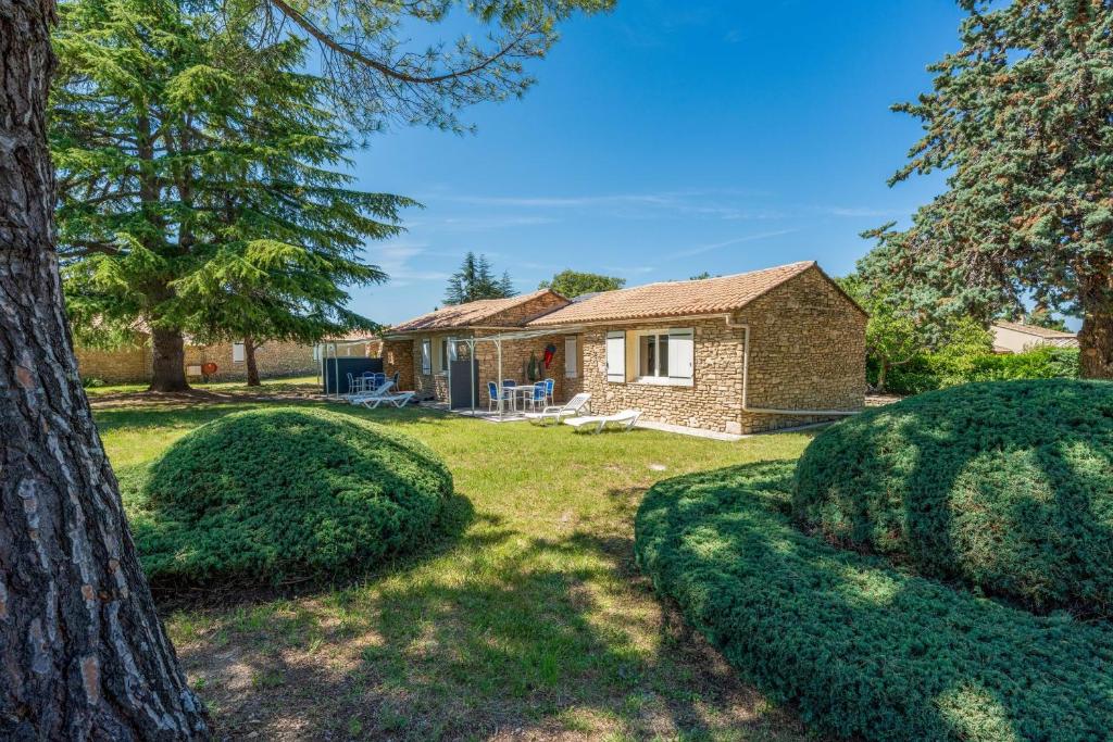 une maison en briques avec un arbre et des buissons dans l'établissement Provencal country house T2 in a tourist residence, à La Roque-sur-Pernes