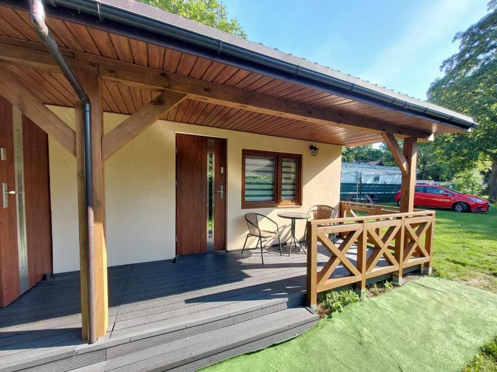 a house with a wooden deck with a table at Domek letniskowy ,,Jolczyn'' in Nowęcin